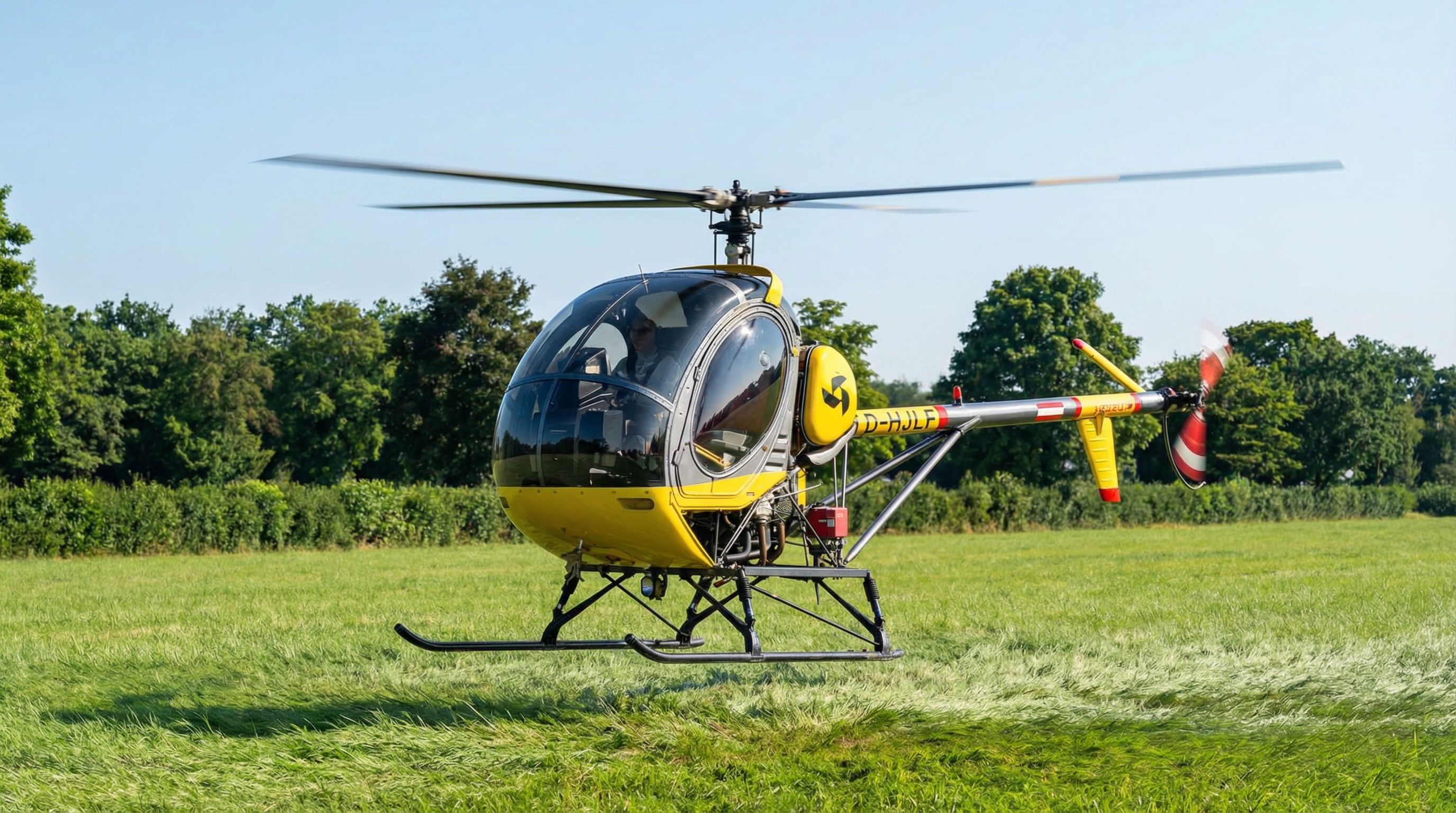 Gelber Hughes 269 Hubschrauber im Schwebeflug über Wiese - Hubschrauberausbildung APEA Stuttgart